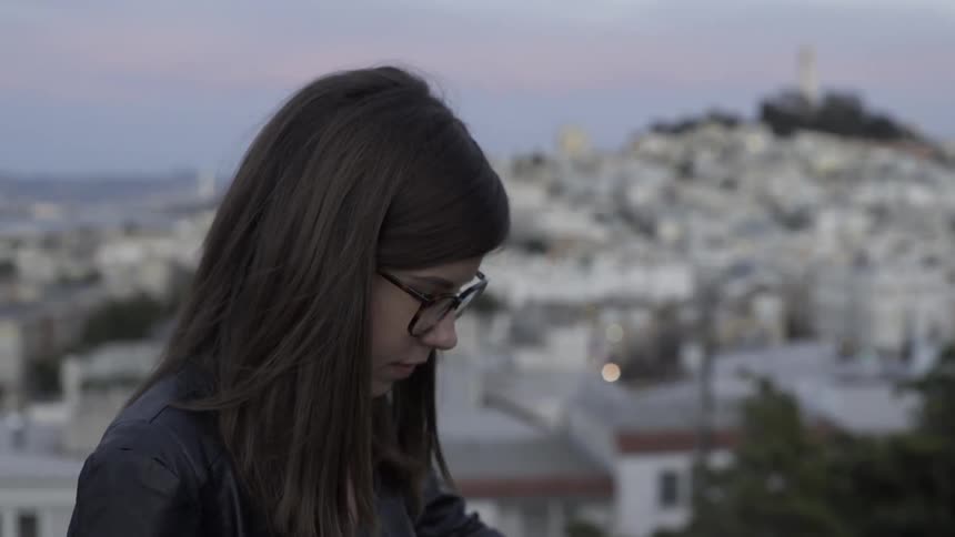 A woman is looking down with a city below on a cloudy day