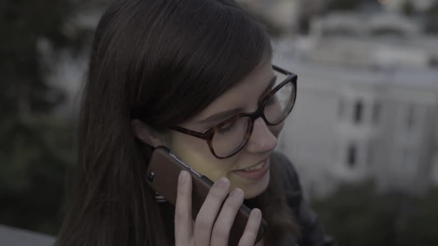 A woman is standing outside talking on a phone