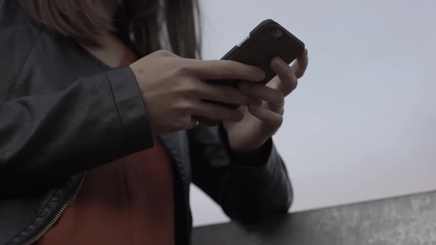 A young woman typing on her phone