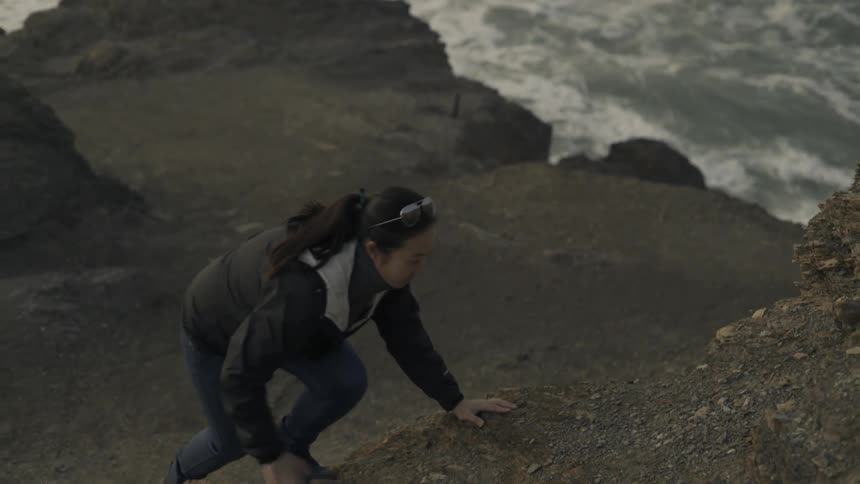 A woman climbing a steep hill near the ocean