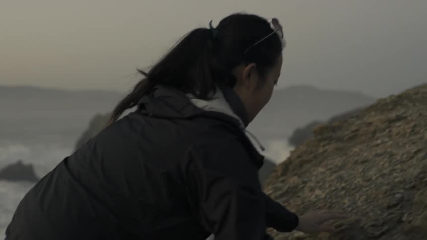 Girl standing on cliff edge overlooking vast landscape with reflective calm mood.