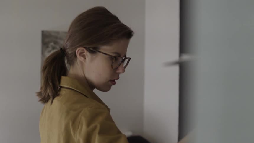 A woman is looking at clothing in a bedroom