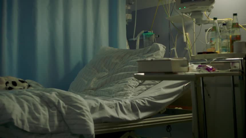 An empty hospital bed surrounded by medical equipment