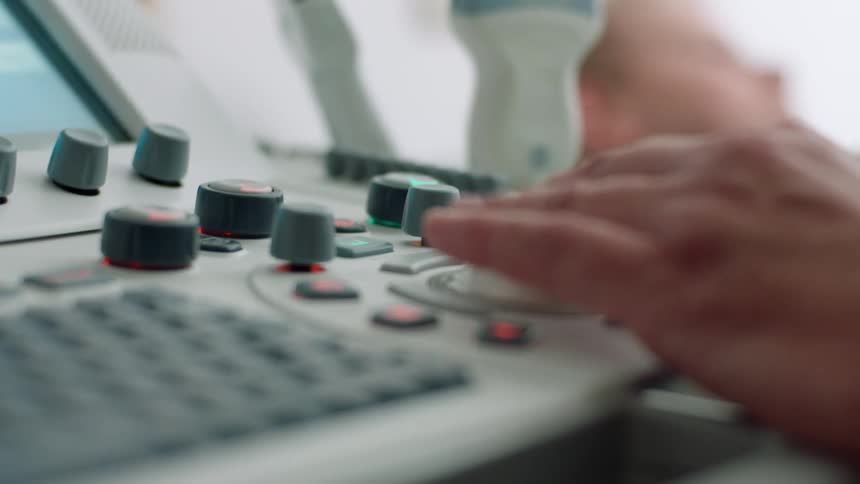 A medical technician uses the keyboard on an ultrasound machine