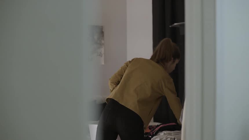 A woman sorts clothing in a bedroom