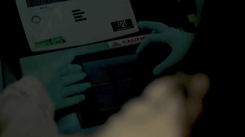 A lab worker wearing gloves adjusts a piece of film and glass on a scanner