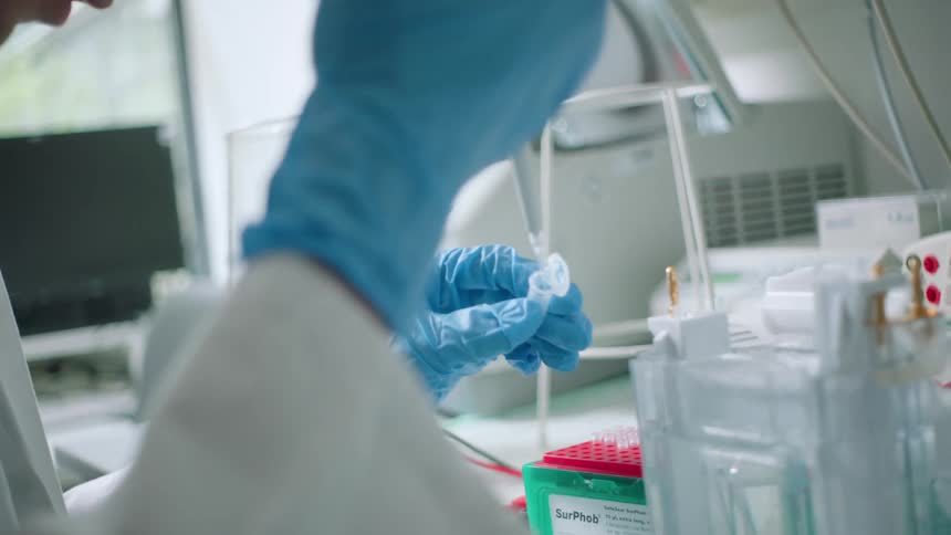 A lab technician transfers a liquid into a test tube
