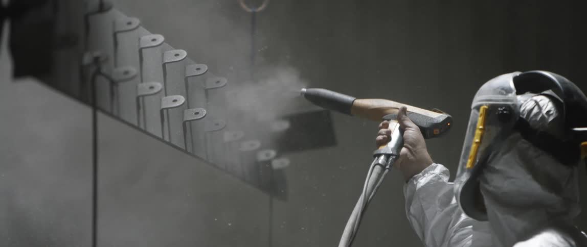 A painter uses a painting gun to spray a piece of metal