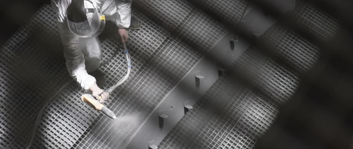 Worker uses a sprayer to spray some metal