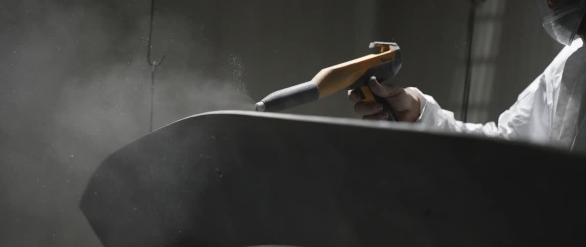 A person with a protective suit using a hose like device that emits smoke
