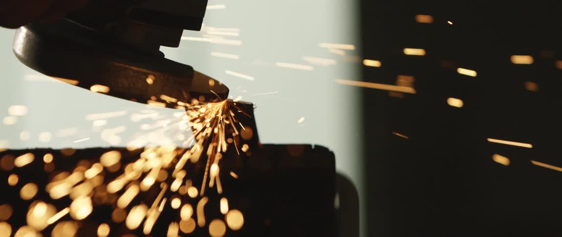 A sander moves across a piece of material and kicks off sparks