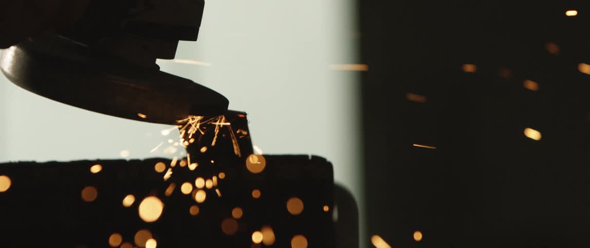 A sander moves across an object and throws off sparks