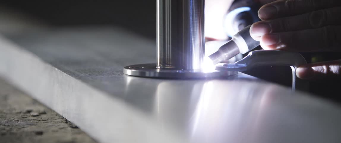 A person uses a tool with a bright light to drill into a chrome post