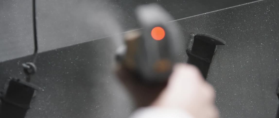 A man uses a pressure washer to spray metal
