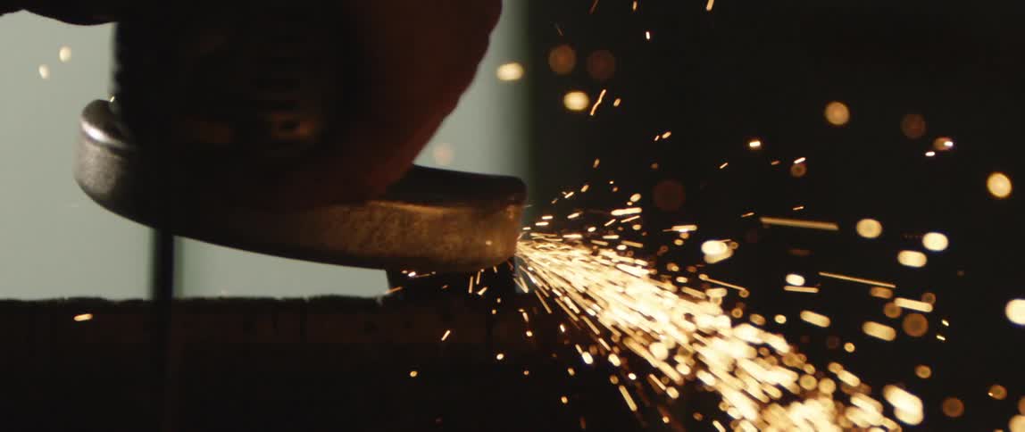 Handheld power tool working on metal showers sparks into shadowy room