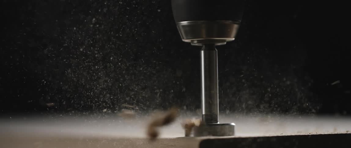 A drill digs into a wooden board