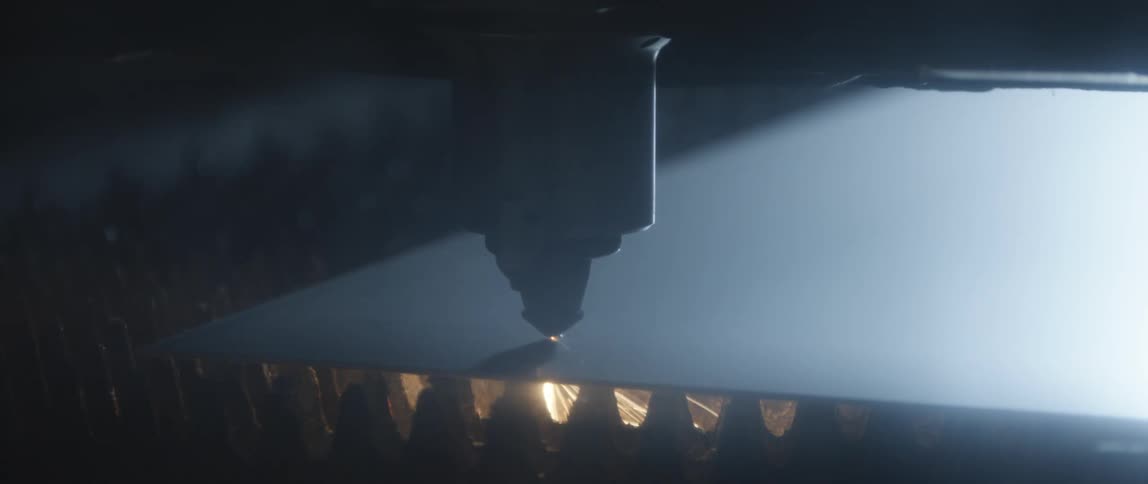 An automated spot welder moves over a piece of metal