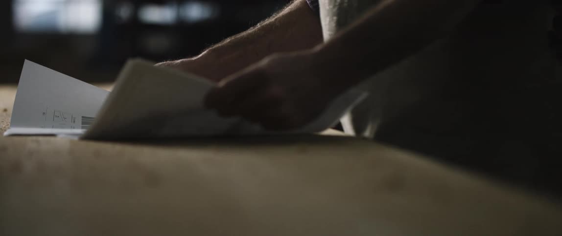 A white man spreads papers on the top of a wooden table