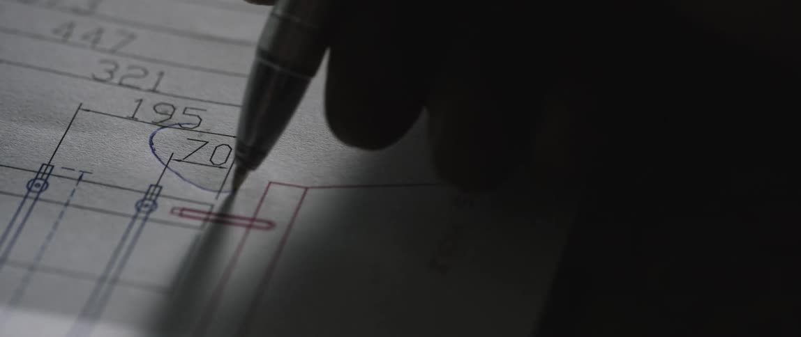 Person writing with a pen on a blueprint