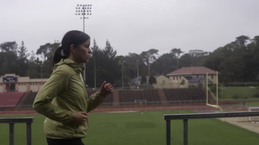 A woman slowly jogging in the bleachers of a track stadium