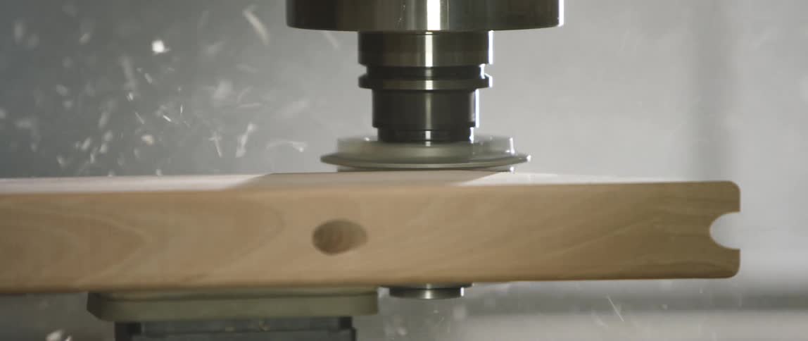 Machine cutting piece of wood on workbench