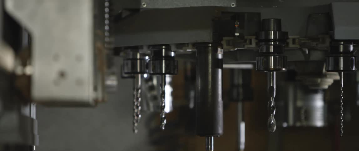 A machine with drill bits spins in a factory