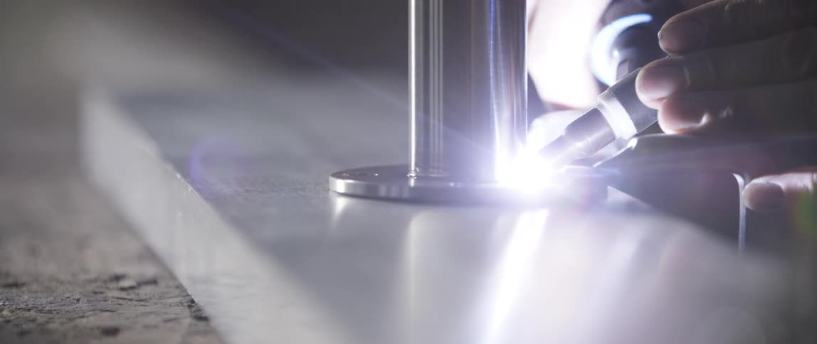 A person with a torch welding a steel pipe