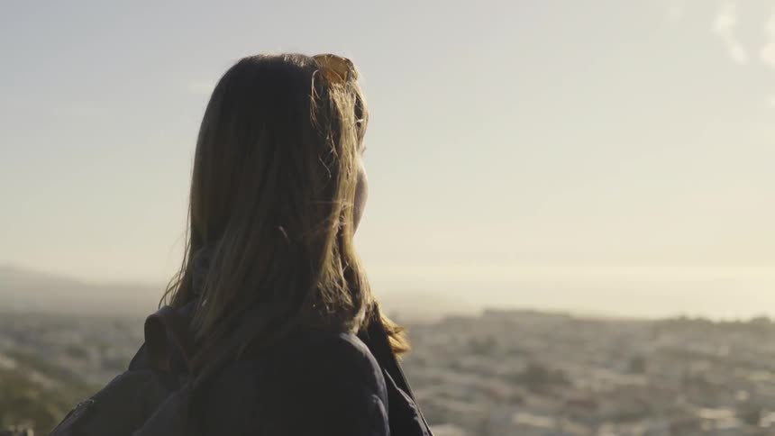 A woman overlooks a city valley on a sunny day