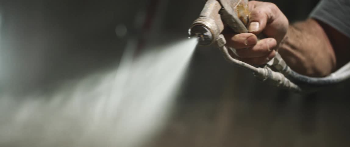 A white man sprays a mist with a handheld sprayer
