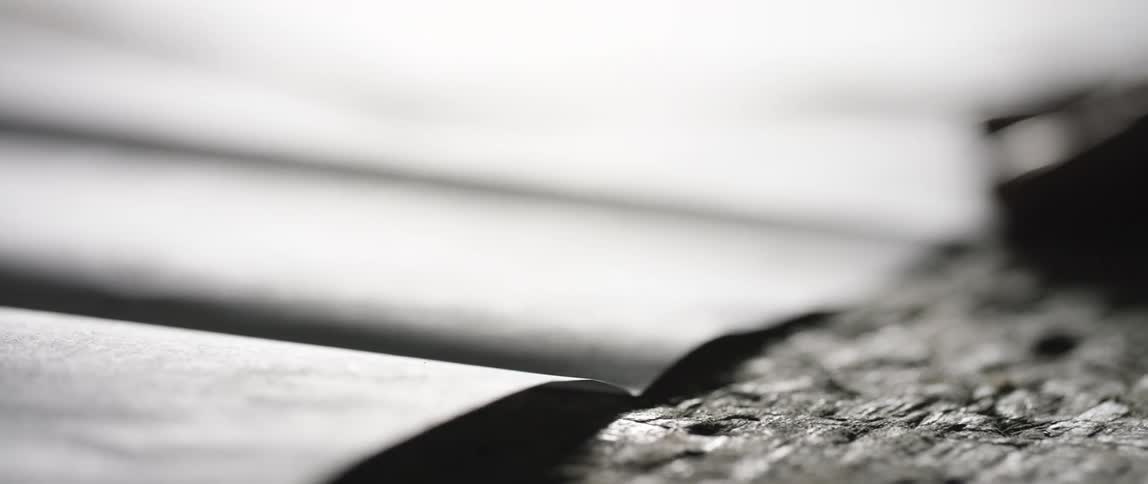 A white man rubs his hand over papers spread out on a wooden table