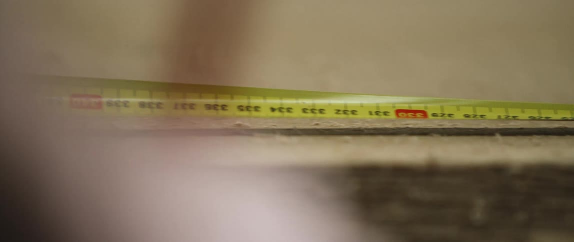 A person measures wood and makes a mark