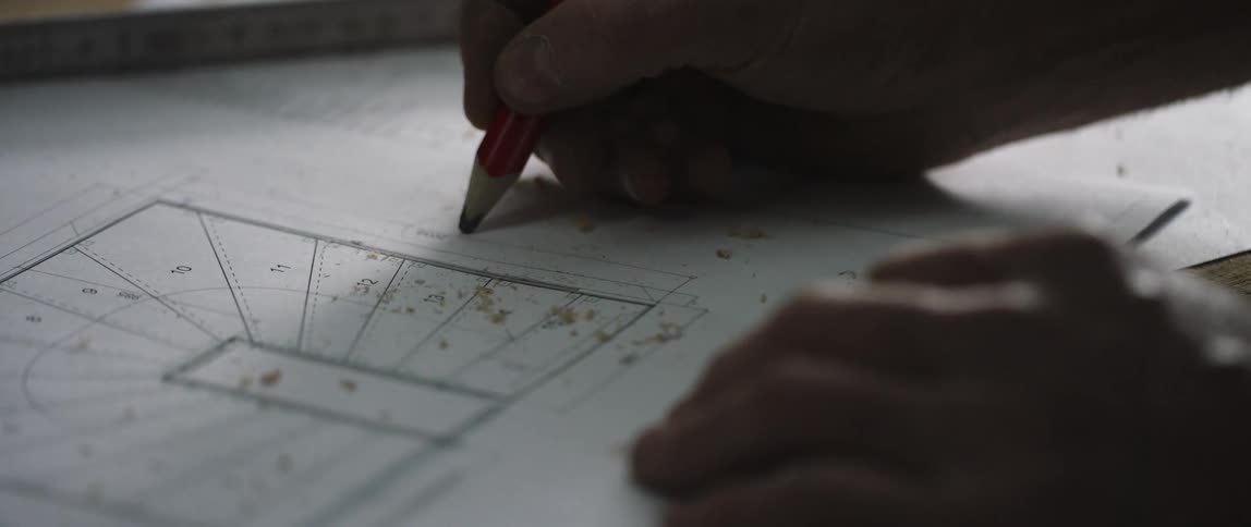 A white man draws on a piece of paper with a pencil