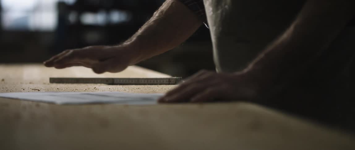 A man spreads some paper on his work bench