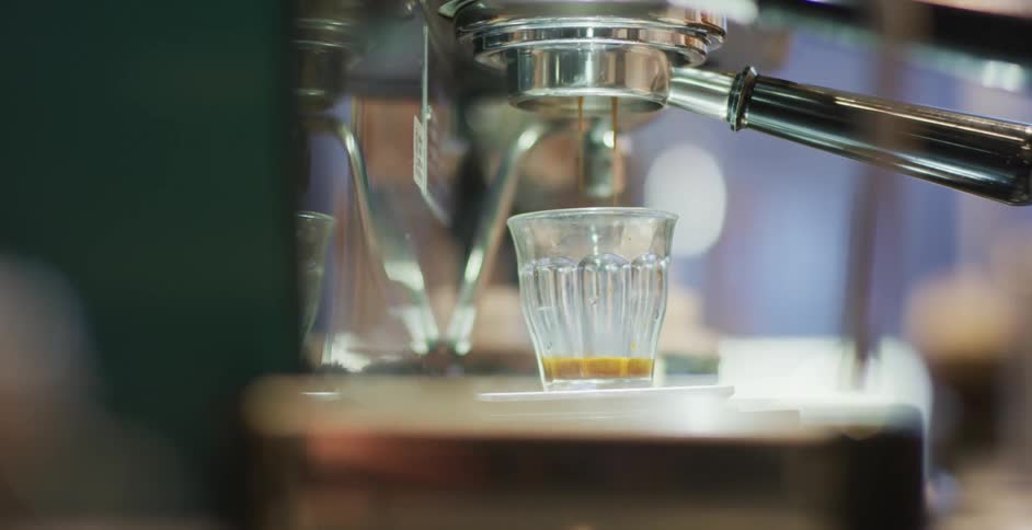 A machine dripping a steaming liquid into a drinking class
