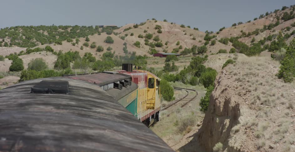 Train follows tracks through rough mountainous scrubby terrain