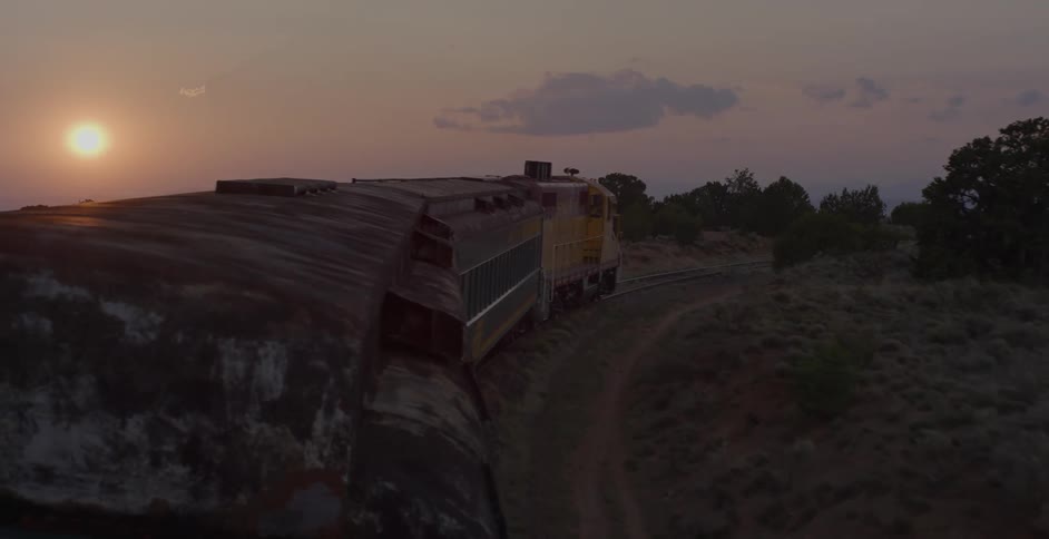 A freight train goes past a forest and around a curve