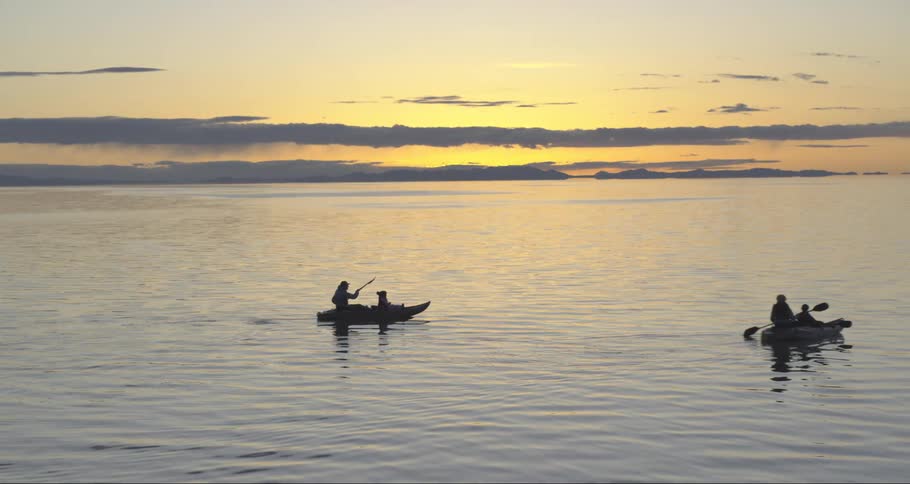 People with boats and paddles on a lake with the sky in the background