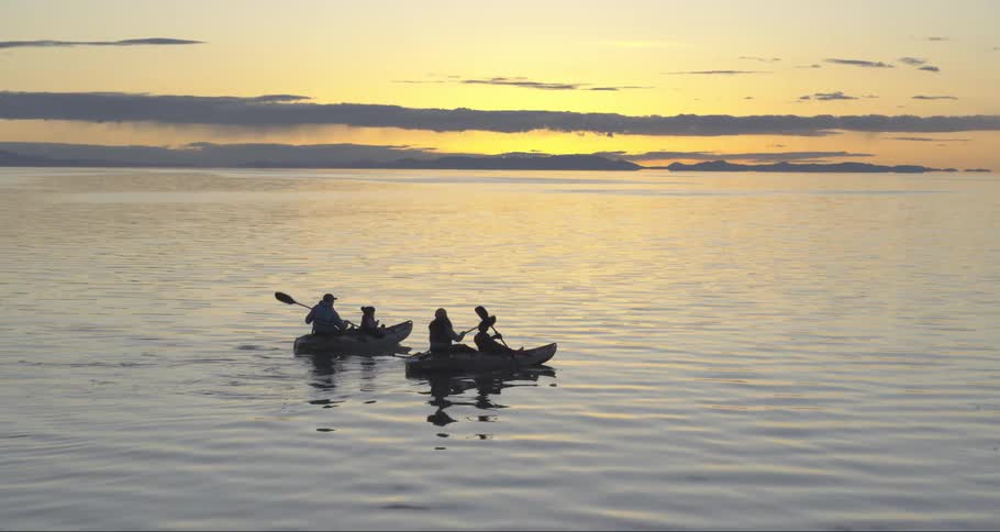 Family kayaking in the ocean at sunrise