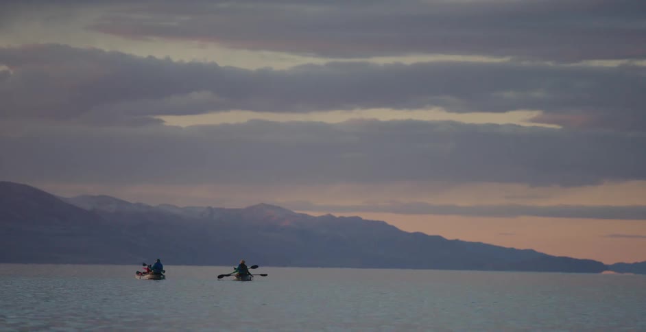 People paddle across a lake on canoes