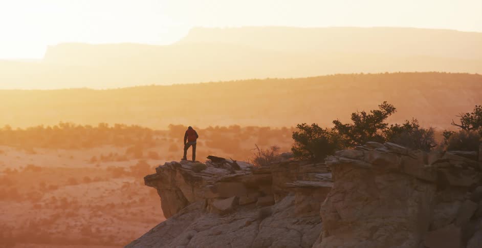 A hiker and his dog walk out onto a rocky outcropping