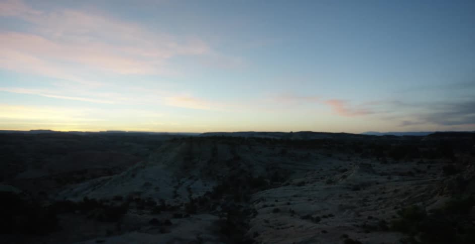 Man and dog stand on top of a mountain as they look out at the land below