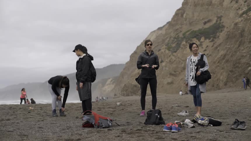 A group of people are standing and sitting on a beach