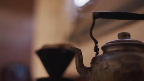 A tea kettle sits on a stove as steam pours out of its spout