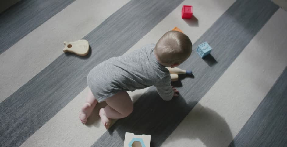 Baby crawling on the floor of a room surrounded by toys