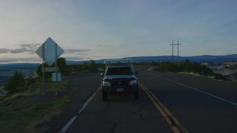 A truck drives down a road surrounded by boulders and shrubbery