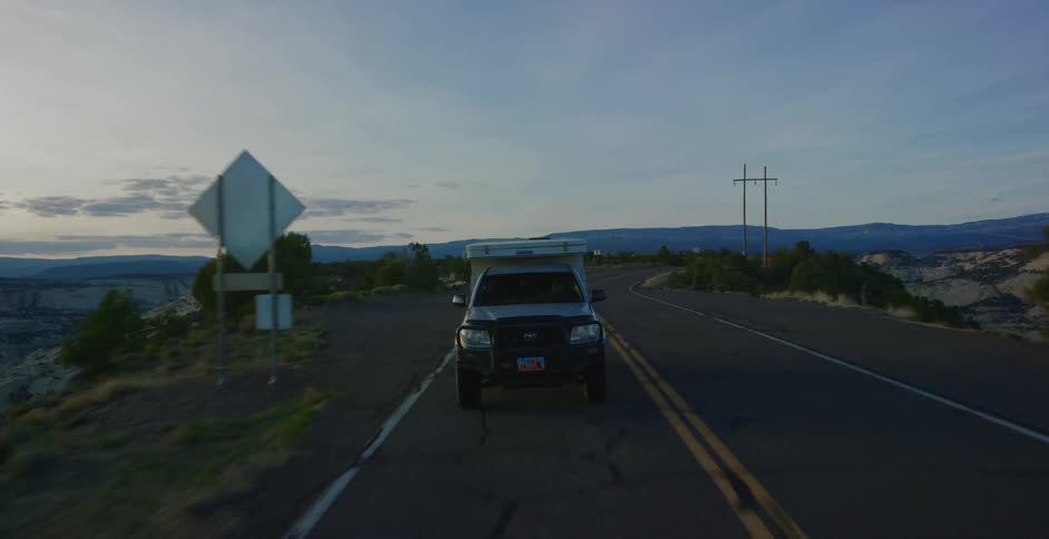 A truck drives down a road surrounded by boulders and shrubbery