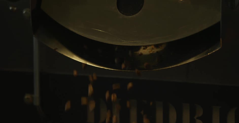 Coffee beans drop from a machine as a worker walks by