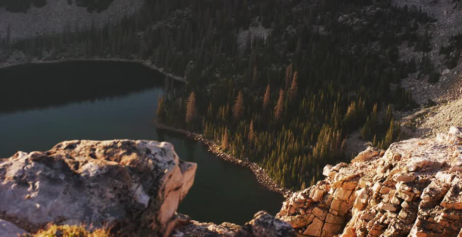 Rough rocky cliff overlooks lake and conifer forest