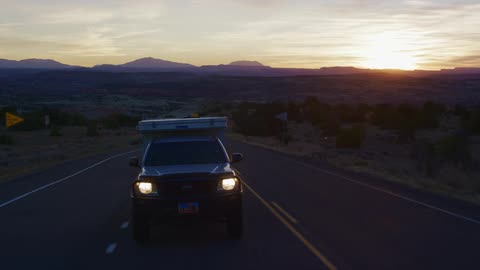 Car traveling on highway through the desert at sunrise