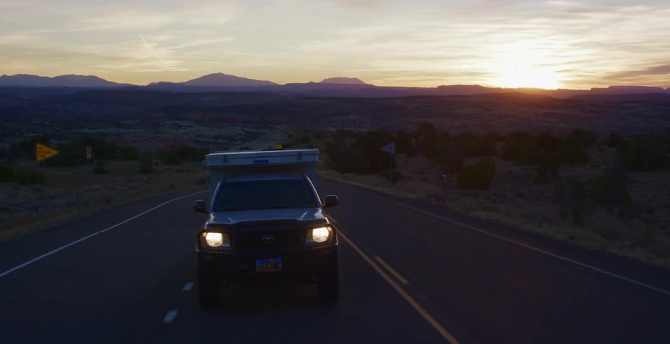 Car traveling on highway through the desert at sunrise